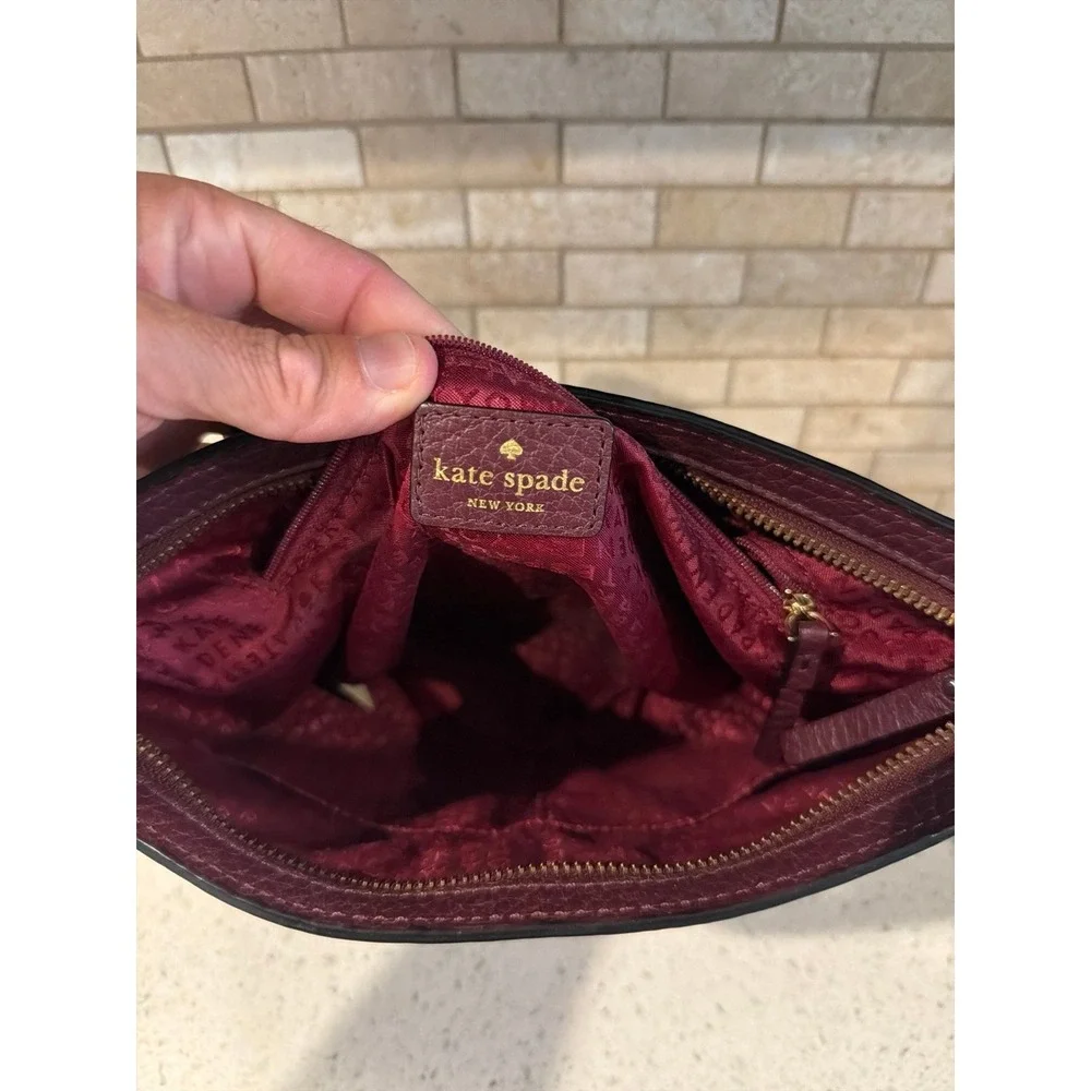 Kate Spade New York pebbled leather crossbody bag in a deep burgundy/wine color.